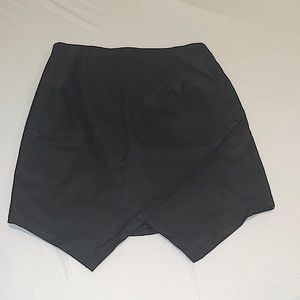 Black faux leather skirt with asymmetrical cut in front. Size S